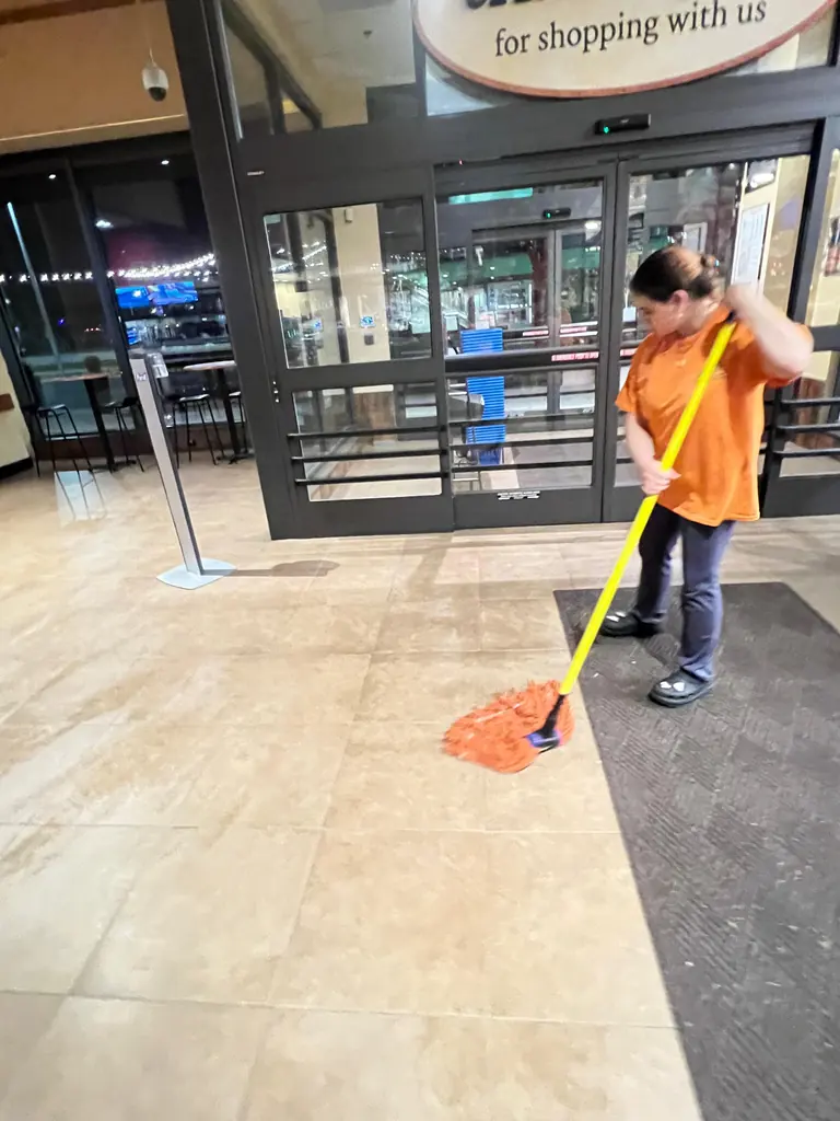 Crew member mopping a store entrance before opening