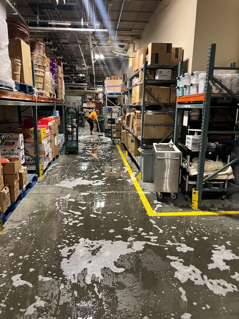 Warehouse floor being deep scrubbed after a spill
