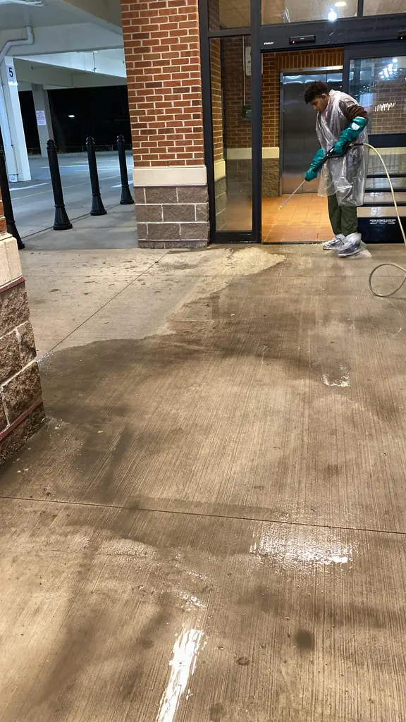 Crew member pressure washing a commercial building entrance