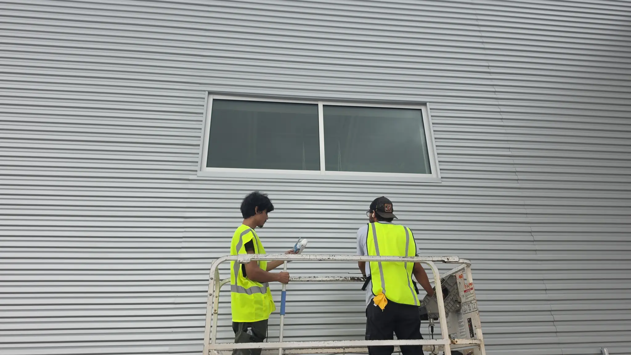 G'Owns crew cleaning high glass from a lift on a commercial building